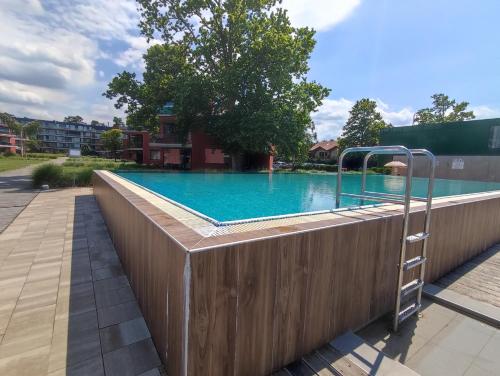 a swimming pool with a wooden fence around it at Soleil Apartmanok Balatonlelle in Balatonlelle