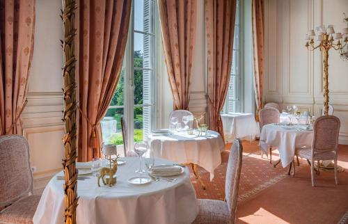 ein Esszimmer mit Tischen, Stühlen und einem Fenster in der Unterkunft Chateau De Rochecotte in Saint-Patrice