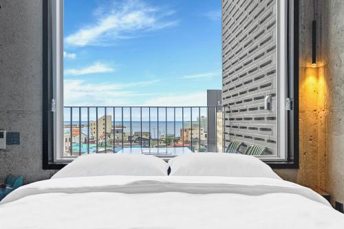 1 dormitorio con cama y ventana grande en Ingu Stay, en Yangyang