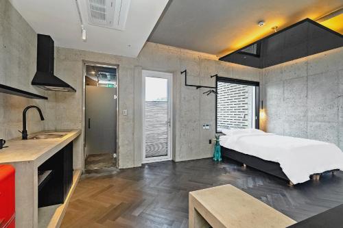 a bedroom with a bed and a kitchen with a sink at Ingu Stay in Yangyang