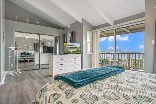 a bedroom with a bed and a television and a balcony at Ka Hale me Ka ike 30 Night Minimum in Kaneohe
