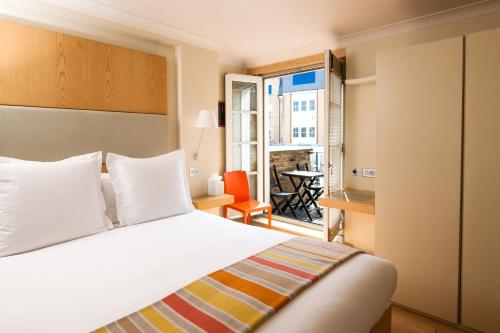 a hotel room with a bed and a balcony at Sydney House Chelsea in London