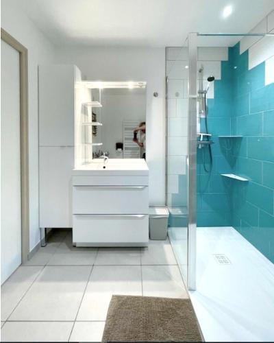 une salle de bain avec un lavabo blanc et une douche dans l'établissement Maison charmante à Saint-Laurent-sur-Mer avec terrasse, à Saint-Laurent-sur-Mer
