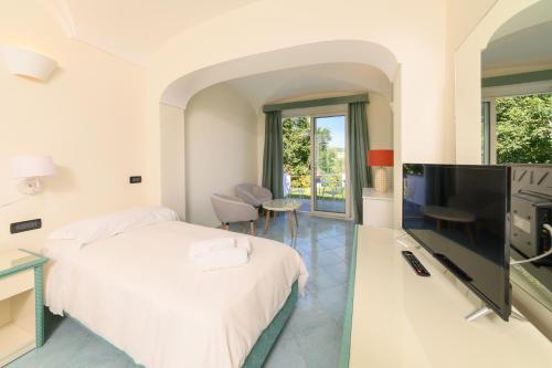 a bedroom with a bed and a flat screen tv at Sorgeto Garden in Ischia