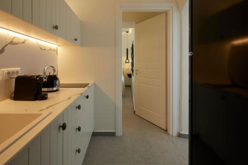 a kitchen with white cabinets and a door leading to a hallway at Lerion Luxury Villas in Akrotiri