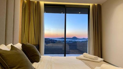 um quarto com uma cama e uma grande janela em Hills Deluxe - Relaxed Luxury in style and serenity em Yalıkavak