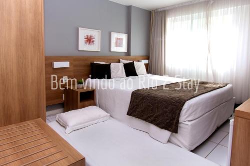 1 dormitorio con 2 camas y ventana en Verano Stay suíte 5 ( Arena e Parque Olimpico), en Río de Janeiro