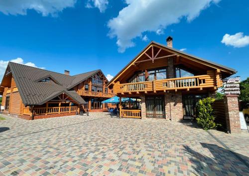 a large wooden house with a brick driveway at Батярський Двір in Pasiky-Zubryts'ki