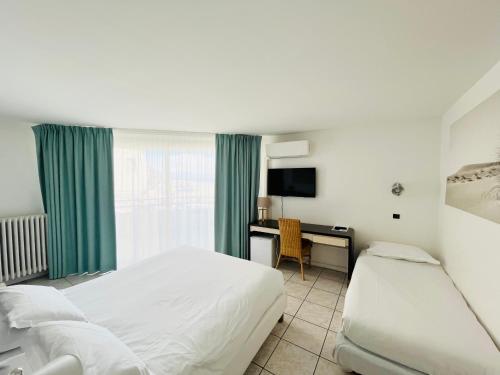 a hotel room with a bed and a desk at Brasilia Hôtel in Palavas-les-Flots