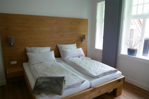 Bett mit weißer Bettwäsche und Kissen in einem Zimmer in der Unterkunft Gulfhof Fresena in Norden