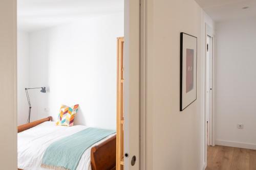 1 dormitorio con cama y pared blanca en El Retiro de San Francisco - Piso de diseño - 4-5 plazas, en Oviedo