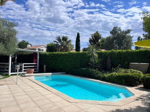 - une piscine dans une cour à côté d'une haie dans l'établissement Villa avec piscine domaine du Golf, à Baillargues