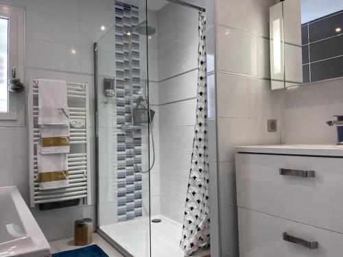 une salle de bain blanche avec une douche et un lavabo dans l'établissement Villa avec piscine domaine du Golf, à Baillargues