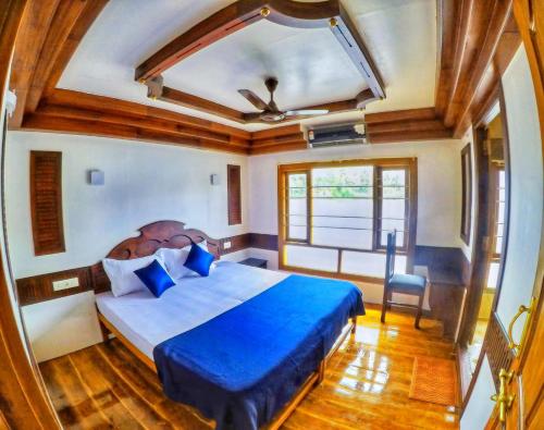 a bedroom with a blue bed and a window at Angel Blue Houseboat Alapuzha in Alleppey