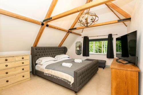 a bedroom with a bed and a flat screen tv at Lodge Farm - Stunning 3 Bed with Large Garden! in Beckley