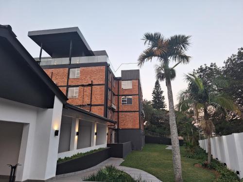 a brick building with a palm tree in front of it at Zar in Amanzimtoti