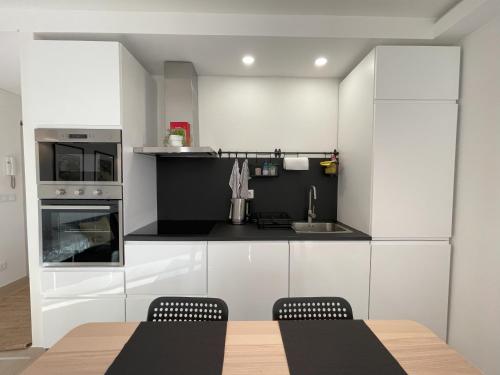 コスタ・ダ・カパリカにあるBlue Houseの白いキャビネット、テーブルと椅子付きのキッチンが備わります。