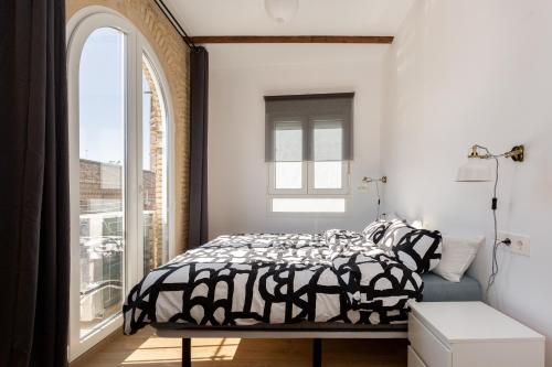 een slaapkamer met een zwart-wit bed en een raam bij SB2 - Apartamento moderno 2 dormitorios, 4º sin ascensor, muy céntrico in Zaragoza