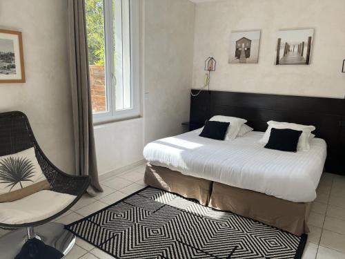een slaapkamer met een bed, een stoel en een raam bij Le Synaya in Sanary-sur-Mer