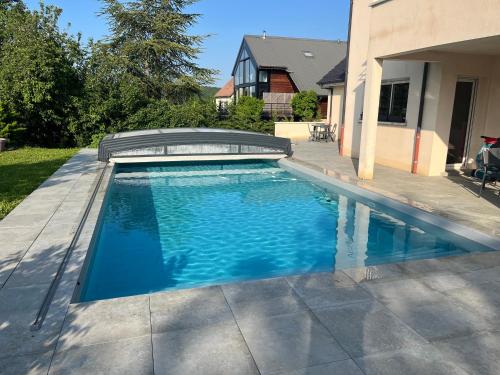 a swimming pool in a yard next to a house at Le Flav - Charmant appartement à 10 mn de Dijon in Flavignerot