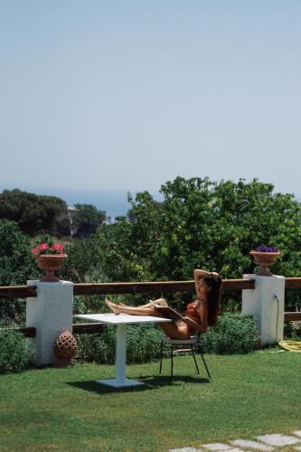 a woman sitting in a chair next to a table at Sorgeto Garden in Ischia
