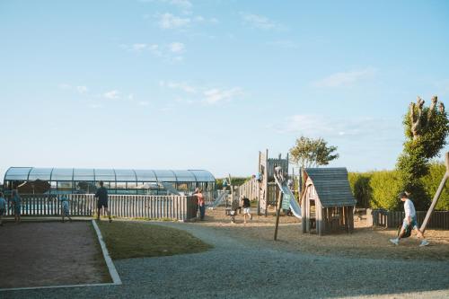 a park with a playground with a slide and people at Huttopia Les Falaises - Normandie in Saint-Pierre-en-Port