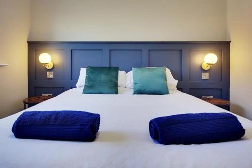 een groot bed met twee blauwe kussens erop bij Windham Mews - Stunning Flat in Seaside Town in Bournemouth