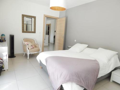 ein weißes Schlafzimmer mit einem Bett und einem Stuhl in der Unterkunft Villa proche de Montpellier et des plages in Castelnau-le-Lez