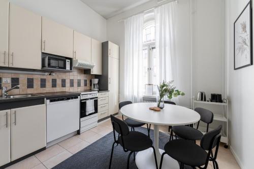 a white kitchen with a white table and chairs at 2ndhomes Tampere "Ruuskanen" Apartment - 3 Bedrooms, Best Location & Sauna in Tampere