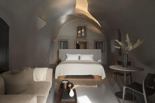 a bedroom with a bed and a living room with a couch at Kivotos Santorini in Imerovigli