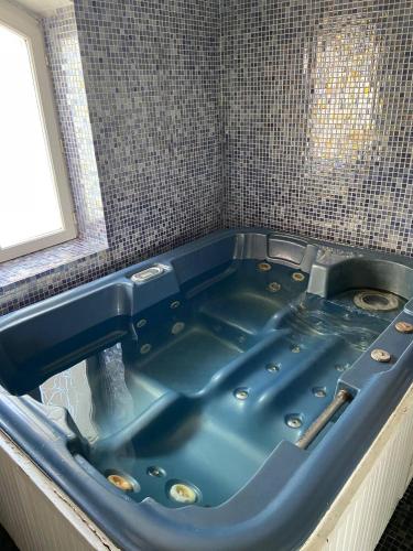 La salle de bains est pourvue d'une baignoire bleue et d'un lavabo. dans l'établissement mas pour 10 personnes avec jacuzzi, à Alès