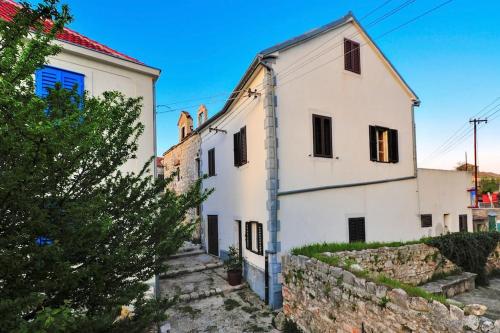 a white house on a hill with a stone wall at Apartment 'Dan' in Zlarin