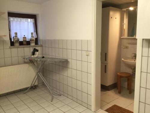 a white tiled bathroom with a sink and a mirror at Ferienhaus Barth in Bad Salzungen