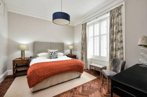 1 dormitorio con cama, escritorio y ventana en 24a Murray Park, en St Andrews