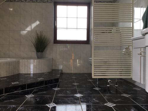 a bathroom with a black tiled floor and a window at Ferienhaus Barth in Bad Salzungen