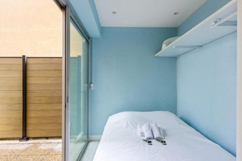 - une chambre avec des murs bleus et un lit avec des draps blancs dans l'établissement Appartement Undi - Welkeys, à Bandol