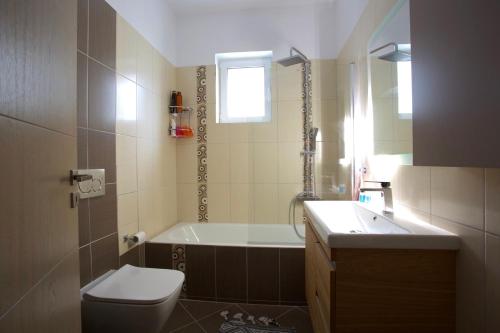 a bathroom with a tub and a toilet and a sink at Το σπίτι της Άρτεμης in Nafpaktos