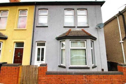 a gray house with a brick fence in front of it at Holiday House for 7 Guests, Free Wi-Fi & Self Check-In Explore Newport in Newport