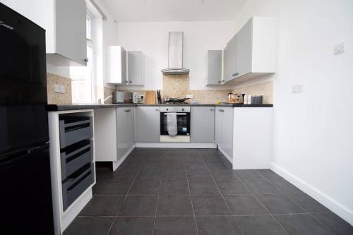 a kitchen with white cabinets and a tile floor at Holiday House for 7 Guests, Free Wi-Fi & Self Check-In Explore Newport in Newport