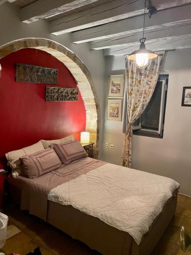 een slaapkamer met een groot bed met een rode muur bij Maison d’Art Monemvasia in Monemvasia
