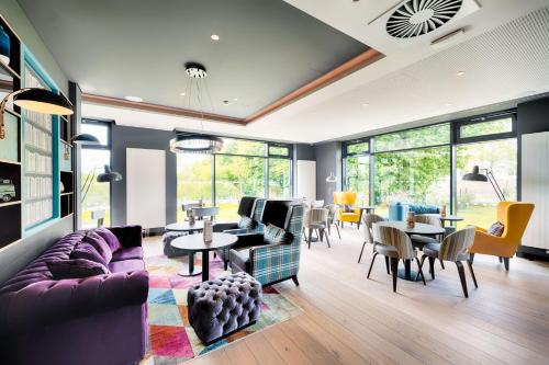 a living room with a purple couch and tables and chairs at Premier Inn Berlin Airport in Berlin