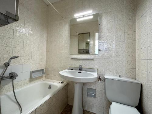 een badkamer met een wastafel, een bad en een toilet bij Apartamentos playa la Perola in Roses