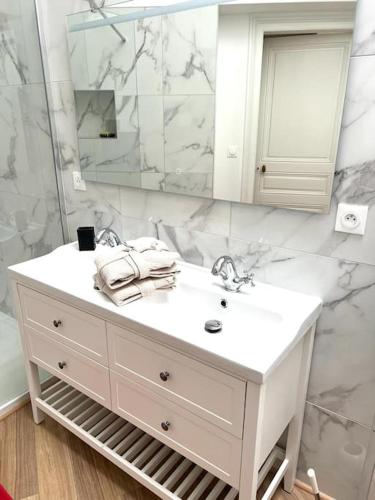 une salle de bain blanche avec un lavabo et un miroir dans l'établissement COSY T3 Centre Reims/Pkg Privé, à Reims