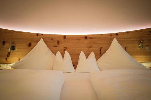 a bunch of white pillows sitting on a bed at Hotel Krallerhof in Leogang