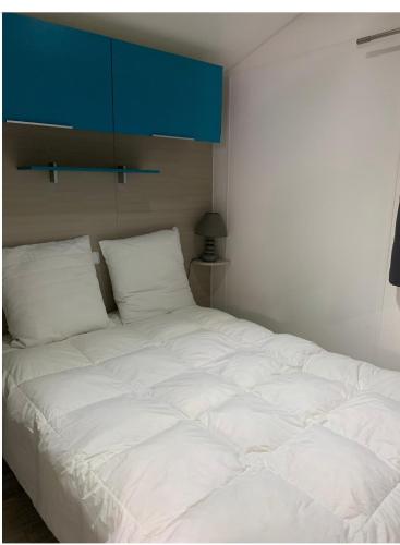 Cette chambre comprend un grand lit blanc et une armoire bleue. dans l'établissement Mobil Home Moderne avec grand terrasse, à Gujan-Mestras