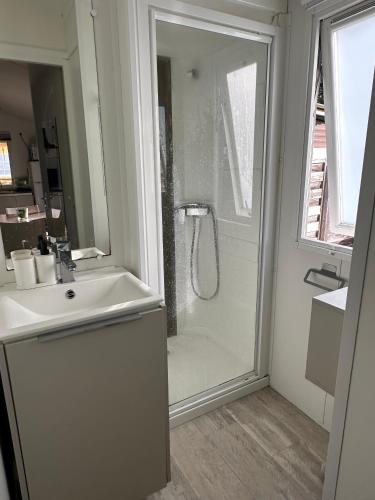 une salle de bain blanche avec une douche et un lavabo dans l'établissement Mobil Home Moderne avec grand terrasse, à Gujan-Mestras