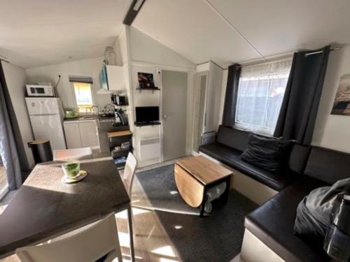 Il comprend un petit salon avec une table et une cuisine. dans l'établissement Mobil Home Moderne avec grand terrasse, à Gujan-Mestras