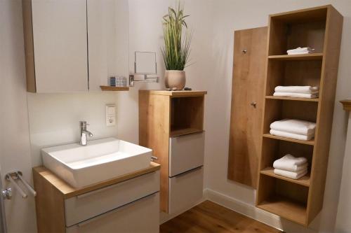 a bathroom with a sink and a shelf with towels at Gulfhof Fresena in Norden