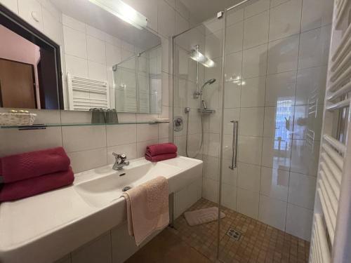 uma casa de banho branca com um lavatório e um chuveiro em Ferienwohnungen im Haus Sonnleiten am Weissensee em Techendorf