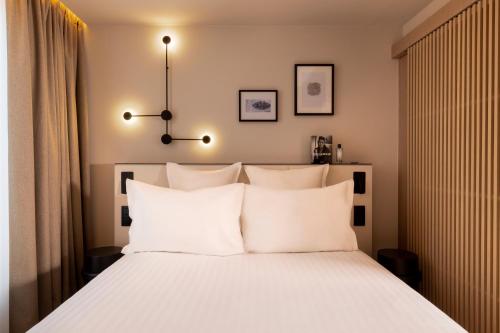 a bedroom with a white bed with white pillows at Hôtel Esté in Paris